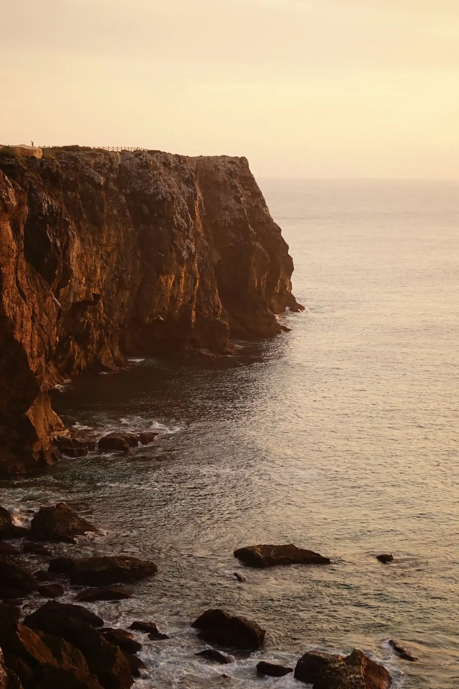 Falésias rochosas junto ao mar ao pôr do sol em Sagres.